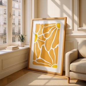 May include: A rectangular framed wall art piece featuring an abstract pattern of yellow and orange organic shapes separated by white lines. The artwork is enclosed in a light-coloured wooden frame and displays a sun-like motif in the corners.