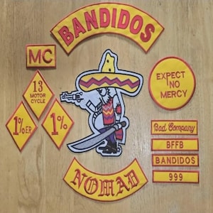 Puede incluir: Un conjunto de parches bordados con detalles en amarillo y rojo. Los parches incluyen la palabra "BANDIDOS", un personaje de dibujos animados con sombrero y frases como "EXPECT NO MERCY" y "NOMAD".