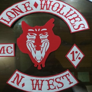 Peut inclure: Ensemble de patchs brodés rouges et blancs. Les patchs incluent les mots "LONE WOLVES" en arc de cercle, une tête de loup, "N. WEST", "MC" et un losange avec "1%" dessus.