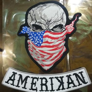 May include: Embroidered patch depicting a skull wearing a bandana in the style of the American flag. The bandana has red and white stripes and a blue section with white stars. A white banner below reads "AMERICAN".