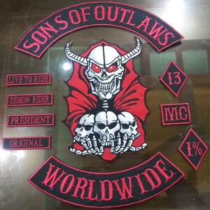 Puede incluir: Un conjunto de parches bordados con temática motera. El parche central presenta una calavera con cuernos y ojos rojos, con las palabras "SONS OF OUTLAWS" y "WORLDWIDE". Parches adicionales incluyen "LIVE TO RIDE", "DEMON RIDER", "PRESIDENT", "ORIGINAL", "13", "MC" y "1%."