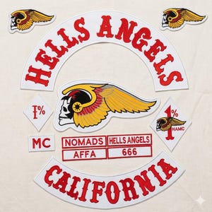 May include: A collection of embroidered patches featuring the words "HELLS ANGELS" in red, arched over a skull with wings. Additional patches include "CALIFORNIA", "NOMADS", "AFFA", "666", and "1%", all in red and white.
