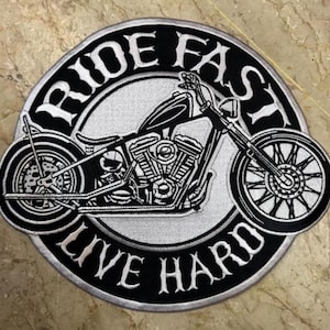 May include: Circular embroidered patch with a black and white motorcycle design. The patch has the words "RIDE FAST LIVE HARD" in white lettering. The motorcycle is detailed with spoke wheels and is set against a grey background.