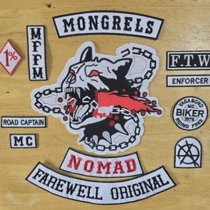 Puede incluir: Un conjunto de parches bordados con varios diseños y texto. El parche central presenta la cabeza de un perro gruñendo con detalles rojos y una cadena. Otros parches incluyen las palabras "MONGRELS", "NOMAD" y "FAREWELL ORIGINAL".