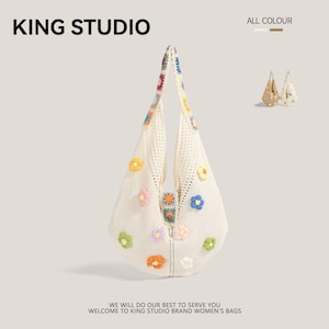 Op de afbeelding: Een crèmekleurige, gehaakte draagtas versierd met kleurrijke bloemenapplicaties. De tas heeft een uniek, open geweven ontwerp en een handvat versierd met extra bloemaccenten. De tekst "KING STUDIO" en "ALL COLOUR" zijn zichtbaar.