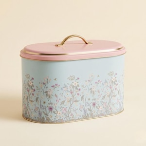Bread box for kitchen counter organization, showing a single large oval farmhouse bread bin in pastel blue with a pink lid and a gold handle, featuring a vintage botanical wildflower design isolated on a clean neutral background for cottagecore rustic home decor styling.