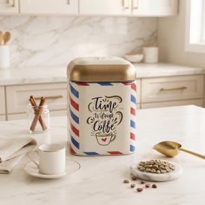May include: A cream-colored rectangular metal canister with a gold lid, featuring red and blue diagonal stripes on the corners and the text "Time to drink Coffee" with a small red heart on a coffee cup illustration printed on the front side.
