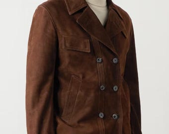 Puede incluir: Chaqueta de ante marrón de doble botonadura. Presenta solapas con muescas, dos bolsillos delanteros y puños abotonados. La chaqueta tiene un diseño clásico con botones oscuros y un corte entallado. El ante tiene un acabado suave y mate.