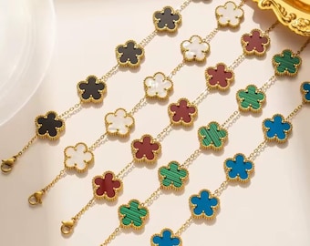 May include: Five gold-tone link bracelets, each featuring a series of flower-shaped charms. The charms are inlaid with various colours including black, white, maroon, green, and blue. Each bracelet is finished with a lobster claw clasp.