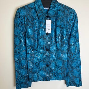 May include: A turquoise and black snakeskin-effect blazer with a collared neckline and three black buttons. The jacket hangs on a black hanger with the brand name "together" printed on it. A price tag is attached.