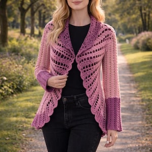 Puede incluir: Chaqueta de crochet hecha a mano, con frente abierto, en tonos rosas y morados. La chaqueta presenta un borde festoneado y mangas largas con un diseño de bloques de color. La modelo lleva un top negro y vaqueros negros.