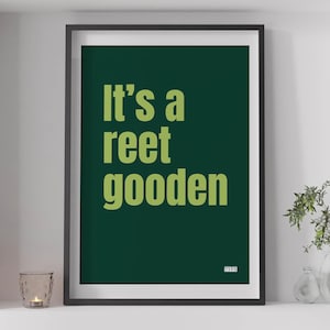 Peut inclure: Une affiche encadrée avec l'inscription "It's a reet gooden" en vert clair sur fond vert foncé. L'impression encadrée de noir est exposée sur une étagère blanche, avec une bougie et des plantes.