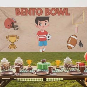 Könnte beinhalten: Eine festliche Outdoor-Partyszene mit einem Banner mit der Aufschrift "BENTO BOWL". Das Banner zeigt Football- und Fußballbilder. Ein Picknicktisch ist mit Tellern, Tassen und Dekorationen gedeckt, darunter Luftballons und ein Kuchen.