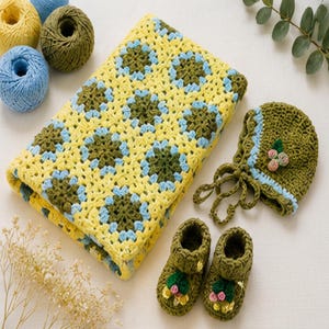 May include: A handmade crochet set featuring a rectangular blanket with a yellow, olive green, and light blue granny square pattern, a matching bonnet with a floral accent, and a pair of small booties with decorative flower embellishments.