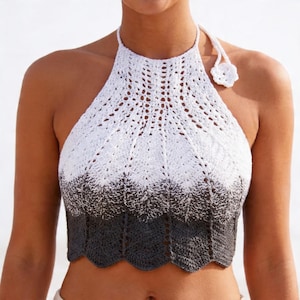 May include: A white, gray, and black crochet halter top with a scalloped hem. The top features a halter neck tie and a small flower detail. The crochet pattern transitions from white to gray and then to black.