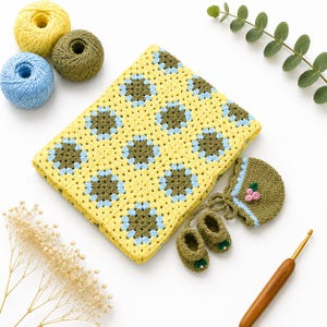 May include: A crocheted blanket featuring a yellow, olive green, and light blue floral granny square pattern, accompanied by a matching olive green bonnet with small pink flower accents and a pair of tiny olive green booties with white beads.