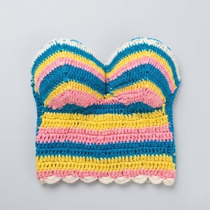 Puede incluir: Top de ganchillo hecho a mano, sin tirantes. Presenta rayas horizontales en azul, rosa y amarillo, con un borde festoneado. El top mide aproximadamente 25 cm de ancho y 20 cm de alto.
