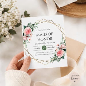 Può includere: Un biglietto d'invito bianco con linee geometriche dorate e accenti floreali. Il testo recita "MAID OF HONOR" con la data "Sabato 25 novembre". Il biglietto è decorato con rose rosa e foglie verdi. L'invito è tenuto da una persona.