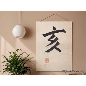 May include: A rectangular wall art print featuring a large black calligraphy symbol on a cream-colored background. The print includes a small red stamp and the text "Digital Download" at the bottom. The artwork is hung with a wooden hanger.