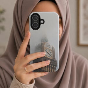 Peut inclure: Coque de téléphone gris clair avec une photo de la Tour Elizabeth, également connue sous le nom de Big Ben, dans le brouillard. L'étui a une découpe pour un appareil photo à double objectif et un bord noir. La personne porte un hijab beige.