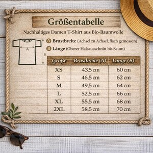 May include: A size chart for a sustainable women's T-shirt made of organic cotton. The chart shows chest width and length measurements in centimetres for sizes XS to 2XL. A straw hat and sunglasses are in the background.