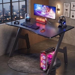 May include: A black carbon fibre patterned gaming desk with Z-shaped legs, featuring a computer monitor displaying a rocket, a mechanical keyboard, a mouse, a headset on a stand, a glowing nixie tube clock, and a tower PC with red lighting.