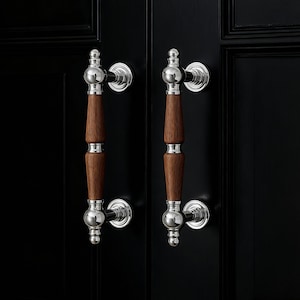 May include: Two door handles with a polished silver finish and a dark wood grip. The handles are mounted on a black door. The handles have a classic, elegant design.