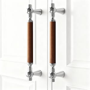 May include: Two cabinet pulls with a polished chrome finish and a central wooden handle. The wooden handle is a warm brown color. The pulls are mounted on a white cabinet door.