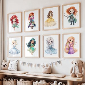 Op de afbeelding: Acht ingelijste aquarelprints van geanimeerde prinsessenpersonages in een kinderkamer. De prints tonen prinsessen met rood, blond en zwart haar, gekleed in jurken in verschillende kleuren. De frames zijn lichtbruin en hangen aan een witte muur.