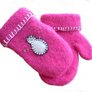 Peut inclure: Une paire de moufles rose vif. Les moufles sont faites d'une matière duveteuse et présentent un appliqué de bonhomme de neige blanc sur une moufle. Des coutures blanches ornent les poignets et le motif du bonhomme de neige. Les moufles sont conçues pour la chaleur et le confort.