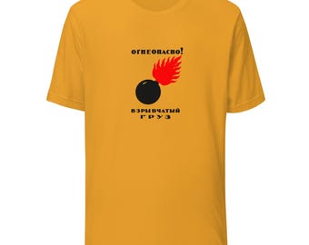 Pode incluir: Camiseta amarelo mostarda com um gráfico de uma bomba preta com uma chama vermelha e texto russo. O texto acima da bomba diz "ОГНЕОПАСНО!" e o texto abaixo diz "ВЗРЫВЧАТЫЙ ГРУЗ".