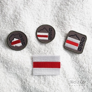 Peut inclure: Écussons brodés avec un motif à rayures blanches et rouges, une montagne et les lettres "GSB". Les écussons sont ronds, carrés et rectangulaires. Le texte "Nici z Gór" est également visible.