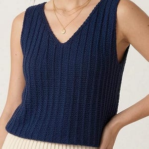 Può includere: Un top senza maniche blu navy a coste con scollo a V. Il top è abbinato a una gonna plissettata color crema. Il top senza maniche ha uno scollo a V profondo e un design senza maniche. La gonna ha pieghe verticali.