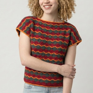 May include: A short-sleeved, crochet top with a wavy pattern in red, gray, and orange. The top has a round neckline and a fitted silhouette. The colors are vibrant and the design is eye-catching. The top is made of a soft, comfortable material.