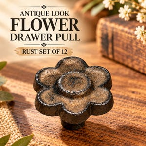 May include: A flower-shaped drawer pull with a dark, textured, rust-colored finish. The text above reads: ANTIQUE LOOK FLOWER DRAWER PULL RUST SET OF 12. The knob features a six-petal design with a raised center and a weathered, cracked surface.