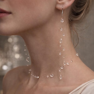 Può includere: Orecchini e collana a goccia d'acqua trasparenti. I gioielli sembrano fluttuare sulla pelle. Gli orecchini pendono dall'orecchio e la collana si drappeggia intorno al collo. Il testo nell'immagine recita: "Invisible Dew Drop Earrings, Floating Water Drop Earrings."