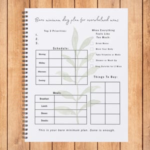 May include: A spiral-bound planner with a minimalist design, featuring a schedule, meal plan, and to-do list. The text reads "Bare minimum day plan for overwhelmed moms." Includes sections for priorities, and things to buy.
