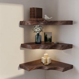 May include: Three wooden corner shelves with a natural edge are mounted on a white wall. The shelves display decorative items, including books, a bird figurine, a vase of flowers, a small painting, candles, and a small dish.