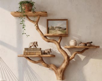 May include: A wooden tree-shaped wall shelf with multiple platforms. The shelves hold a potted plant, framed artwork, decorative items, and books. The tree is made of natural wood and mounted on a light-colored wall.