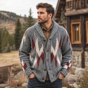Könnte beinhalten: Graue Strickjacke mit Knöpfen, Schalkragen und geometrischem Muster in Weiß, Burgunderrot und Olivgrün. Der Pullover hat ein strukturiertes Strickmuster und wird über einem braunen Hemd getragen.