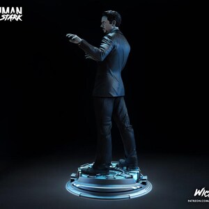 Puede incluir: Estatua de Tony Stark con traje de raya diplom&aacute;tica, de pie sobre una plataforma circular. La figura est&aacute; en una pose din&aacute;mica, con un brazo extendido. Las palabras "Ironman Tony Stark" est&aacute;n en la parte superior izquierda. La palabra "Wicked" est&aacute; en la parte inferior derecha.