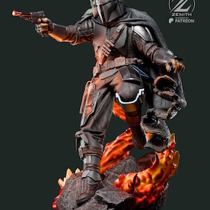 K&ouml;nnte beinhalten: Detaillierte Statue eines mandalorianischen Kriegers in dunkler R&uuml;stung, der eine Blasterpistole mit rotem Licht h&auml;lt. Die Figur steht auf einem felsigen Sockel mit feurigen orangefarbenen und gelben Akzenten. Eine kleine gr&uuml;ne Kreatur befindet sich auf der Schulter des Kriegers.