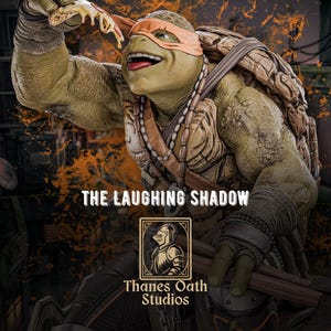 Può includere: Statua dettagliata di una Tartaruga Ninja, con una maschera arancione, che tiene in mano una fetta di pizza. La figura ha un guscio dettagliato e sorride. Il testo "THE LAUGHING SHADOW" e "Thanes Oath Studios" sono visibili.