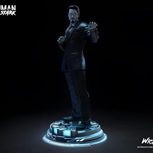 Puede incluir: Una estatua de Tony Stark con un traje oscuro, de pie sobre una plataforma circular con iluminaci&oacute;n azul. Las palabras "Ironman Tony Stark" est&aacute;n en la parte superior izquierda. La estatua es una representaci&oacute;n detallada del personaje.