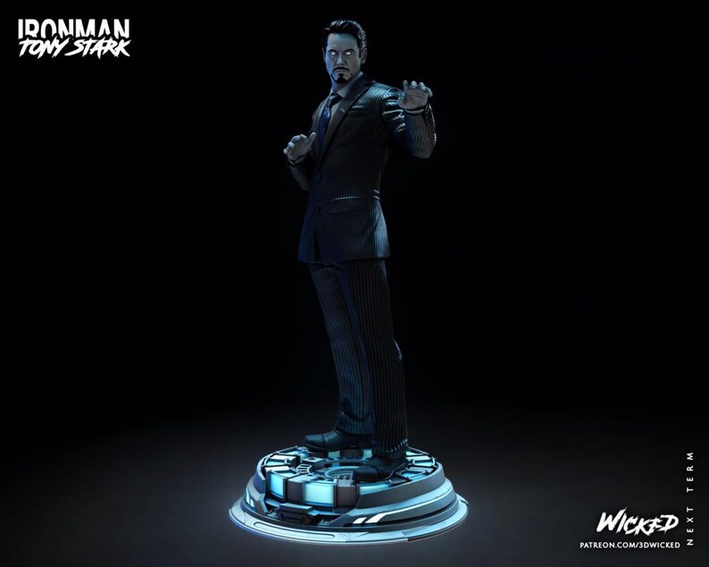 Puede incluir: Una estatua de Tony Stark con un traje oscuro, de pie sobre una plataforma circular con iluminaci&oacute;n azul. Las palabras "Ironman Tony Stark" est&aacute;n en la parte superior izquierda. La estatua es una representaci&oacute;n detallada del personaje.