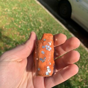 May include: A white ceramic mug with a black handle and the text "But First, Coffee" in a bold, black font. The mug is filled with a dark liquid, likely coffee, and sits on a light-colored surface.
