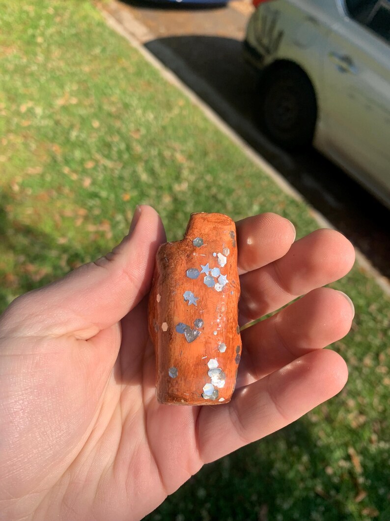 May include: A white ceramic mug with a black handle and the text "But First, Coffee" in a bold, black font. The mug is filled with a dark liquid, likely coffee, and sits on a light-colored surface.