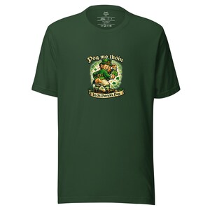May include: Dark green t-shirt featuring a cartoon leprechaun with the text "Póg mo thóin" and "It's St. Patrick's Day." The leprechaun is wearing a green hat and jacket. The shirt is made of a soft material.
