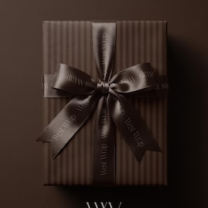 May include: A rectangular gift box wrapped in dark brown paper with vertical stripes, tied with a matching dark brown satin ribbon featuring the repeating text West Wrap. The ribbon is tied in a large bow at the center of the box.