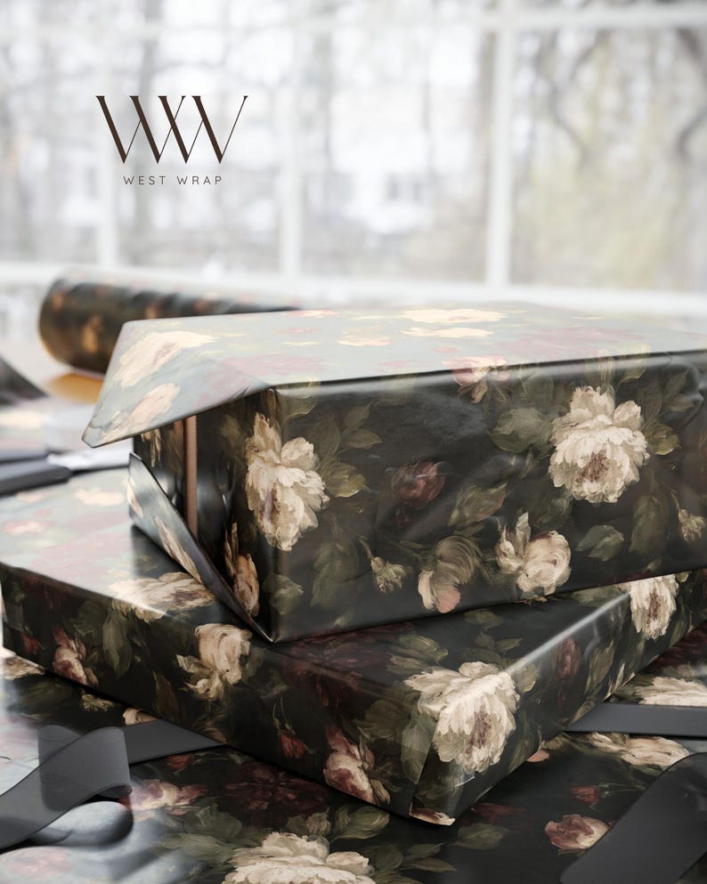 Puede incluir: Dos cajas rectangulares envueltas en papel negro oscuro con un patr&oacute;n floral de rosas color crema, blancas y rojas apagadas con hojas verdes. El logotipo WW WEST WRAP es visible en la esquina superior izquierda sobre las cajas.